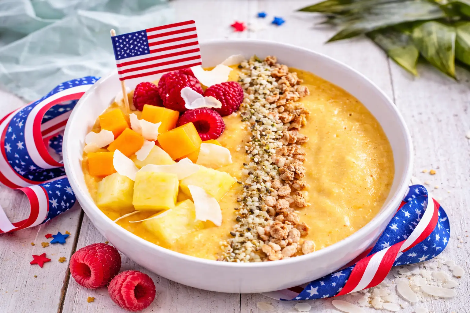 American-style smoothie bowl with hemp seeds, granola, raspberries, mango, pineapple, and coconut flakes.